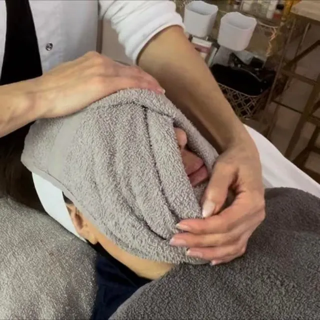 A warm towel pressed to a client's face